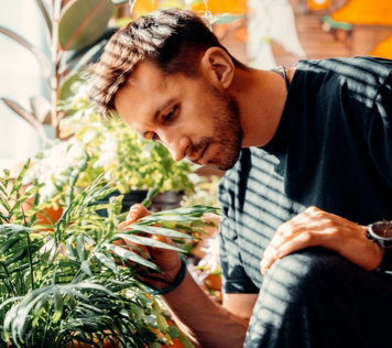 man in black crew neck t-shirt holding green plant