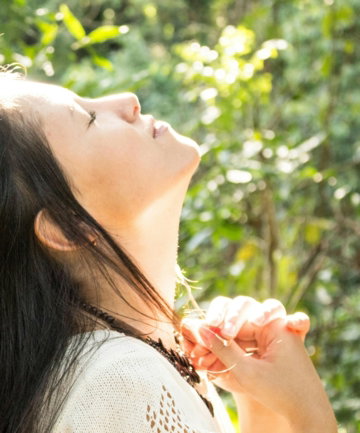 woman standing while closing her eyes and looking up